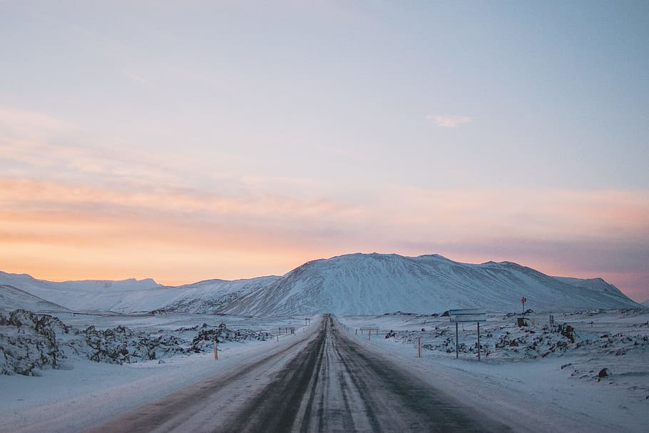 landscape photography of snow covered road and mountain, empty road between snow covered fields