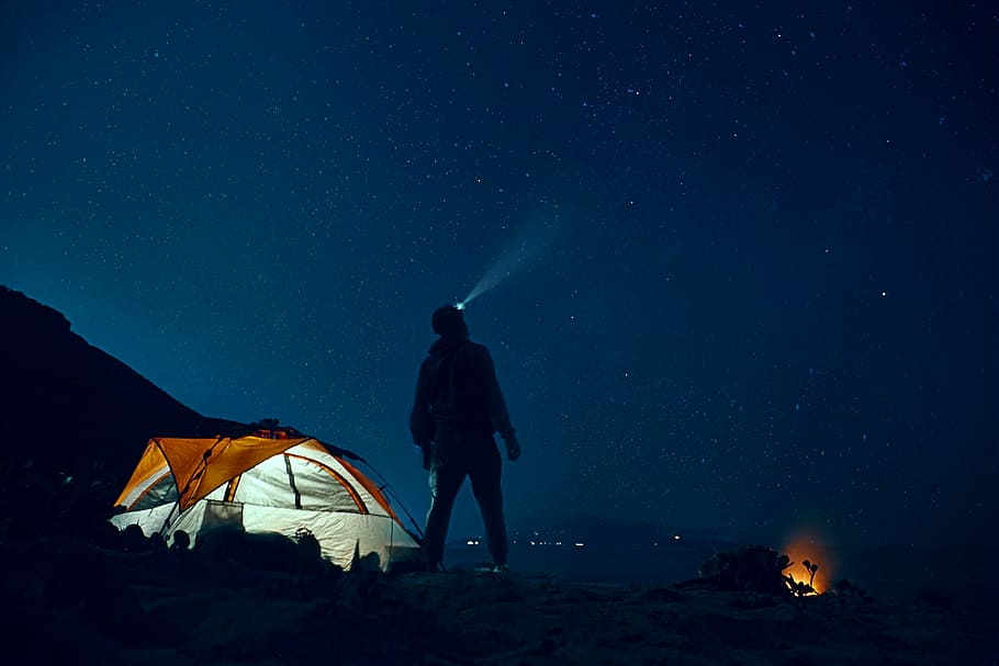 man standing beside camping tent wearing headlamp during nighttime, man using headlamp beside cabin tent HD wallpaper