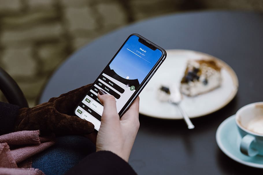 selective focus photography of person using black smartphone, person using iPhone x near the table