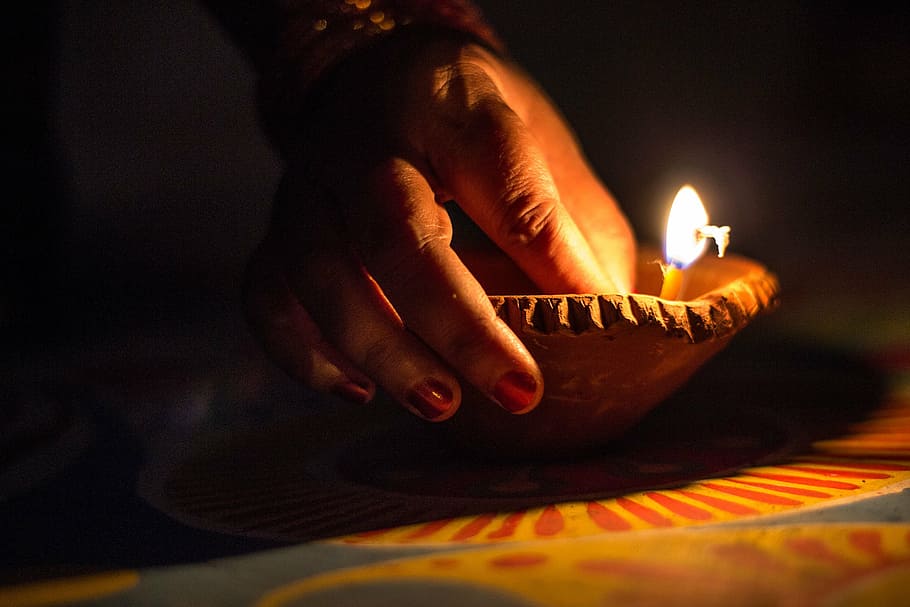 person holding pillar candle, dia, dya, deep, black, light, dark