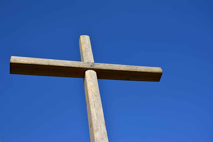 close up photography of brown wooden cross under blue cloudy sky
