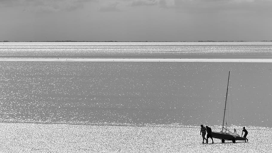grayscale photography of four person carrying boat, sea, hunstanton