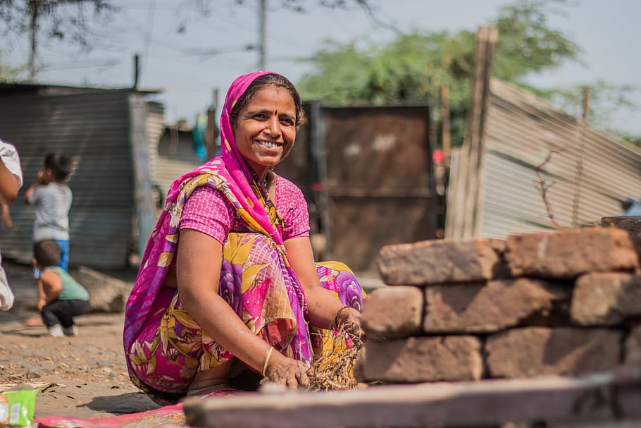 smiling woman sitting near stacked concrete bricks during daytime