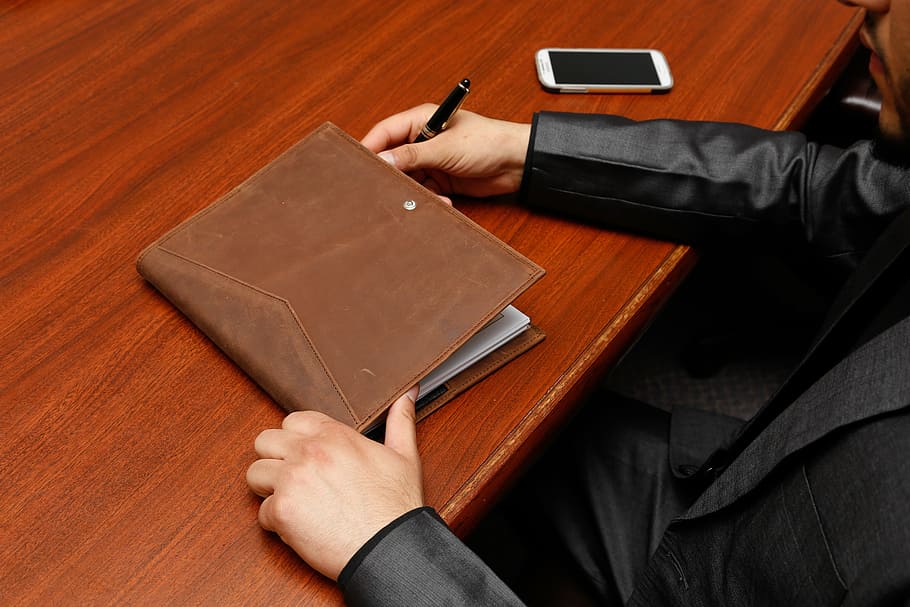 person sitting on beside of brown wooden table, organizer, brown leather HD wallpaper