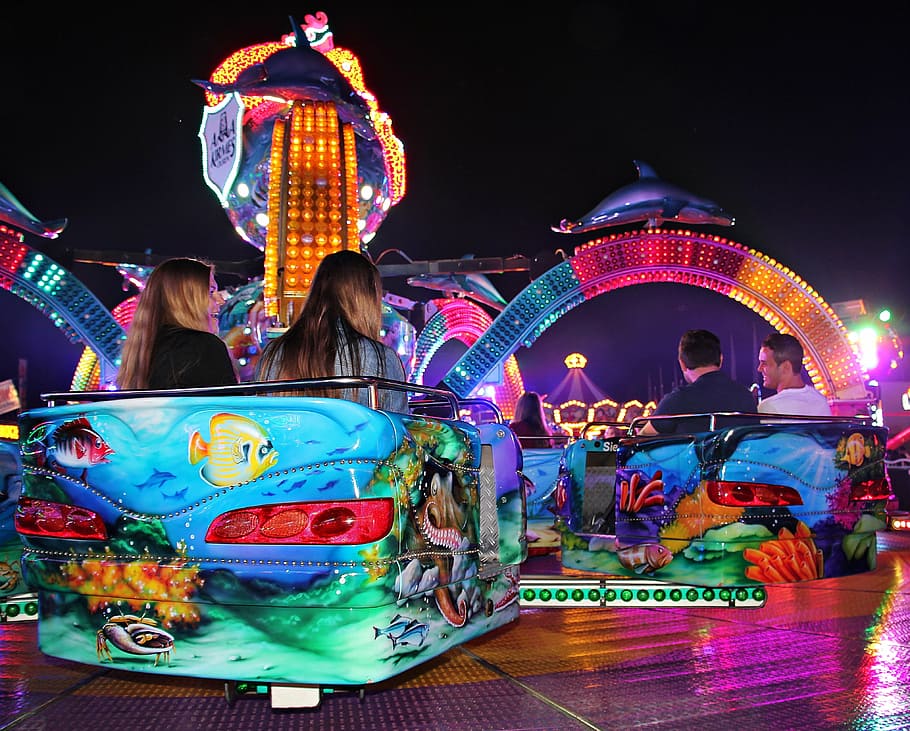 person riding in amusement park during nighttime, fair, hustle and bustle