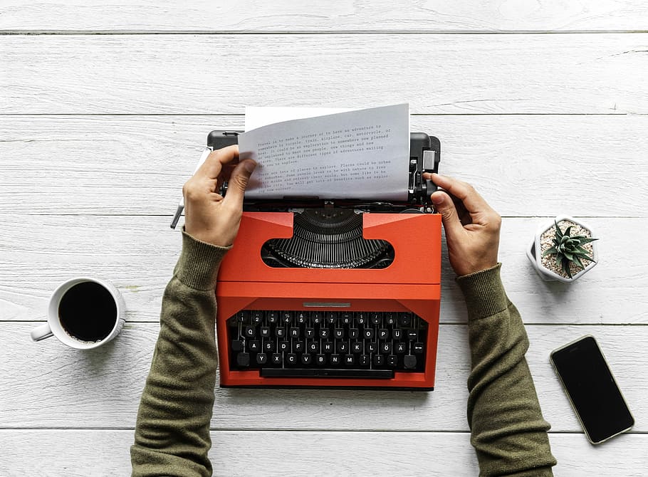 person pulling printer paper on orange typewriter, technology HD wallpaper