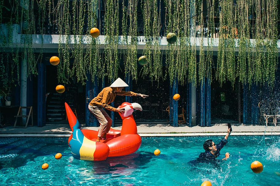 man standing on inflatable scarlet macaw in pool, water, float HD wallpaper