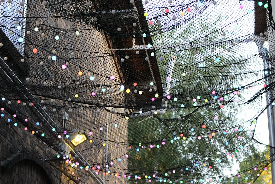string lights between brown houses during daytime, ball string lights with nets during daytime HD wallpaper