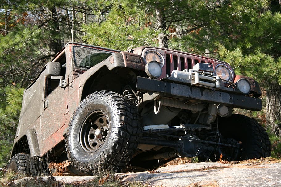 red Jeep Wrangler SUV tackling a rock near trees at daytime HD wallpaper