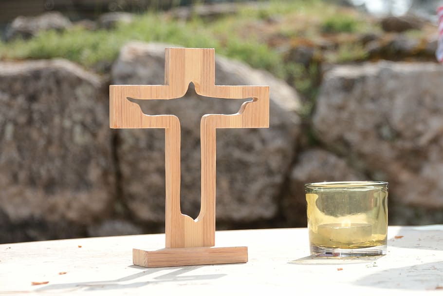 beige wooden cross beside glass candle holder, altar, worship