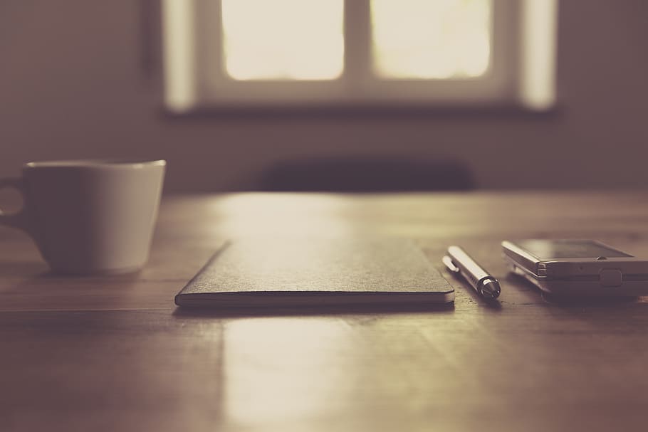 selective focus photo of book and pen on wooden table near mug and smartphone, HD wallpaper