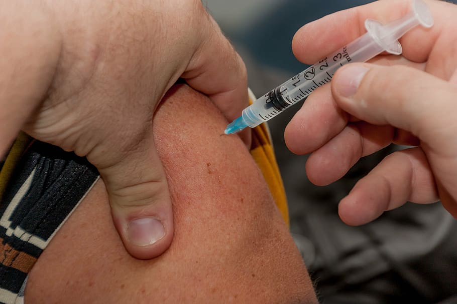 person holding syringe while injected to skin, flu shot, needle