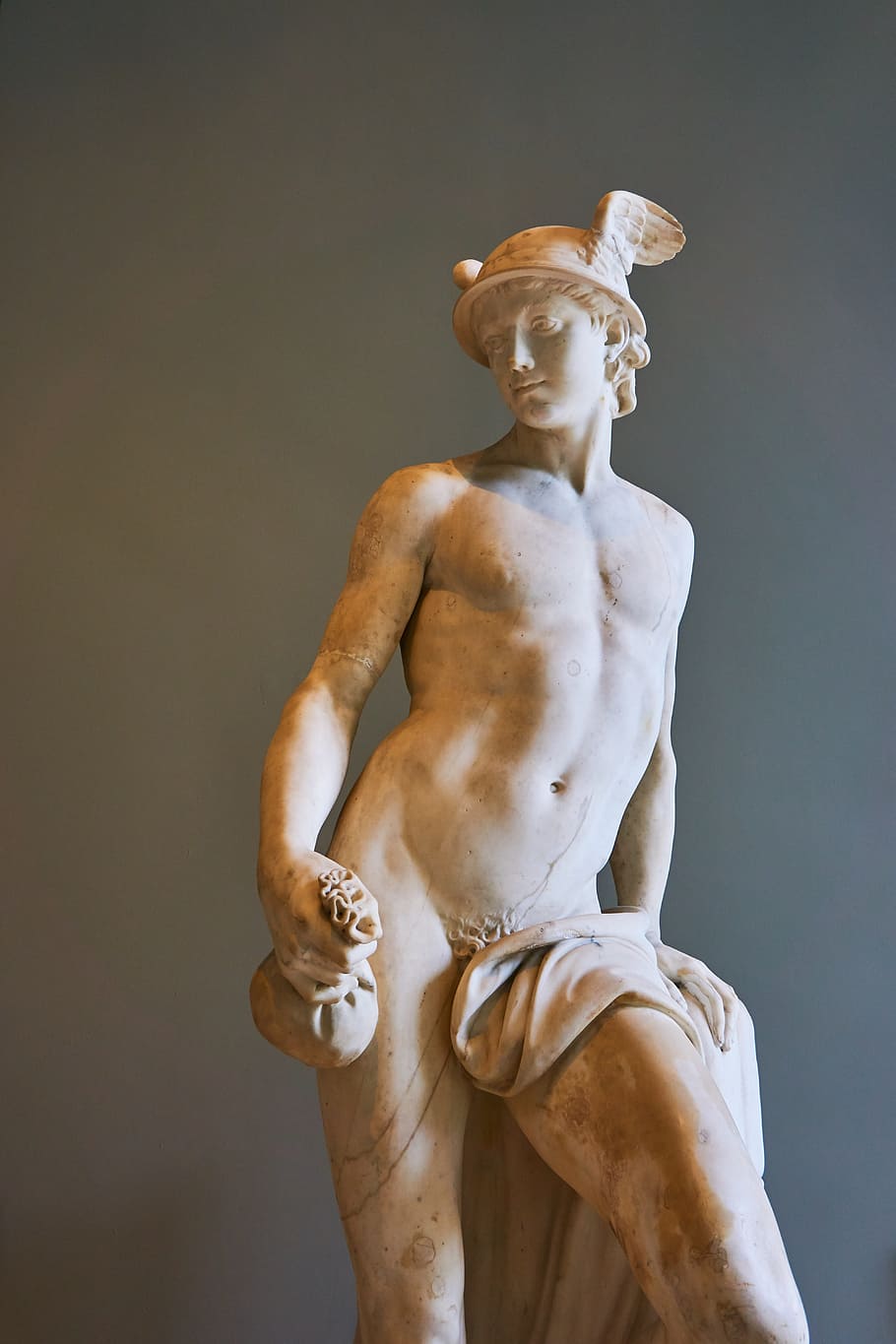 male Greek God statue near gray wall, louvre, paris, museum, france