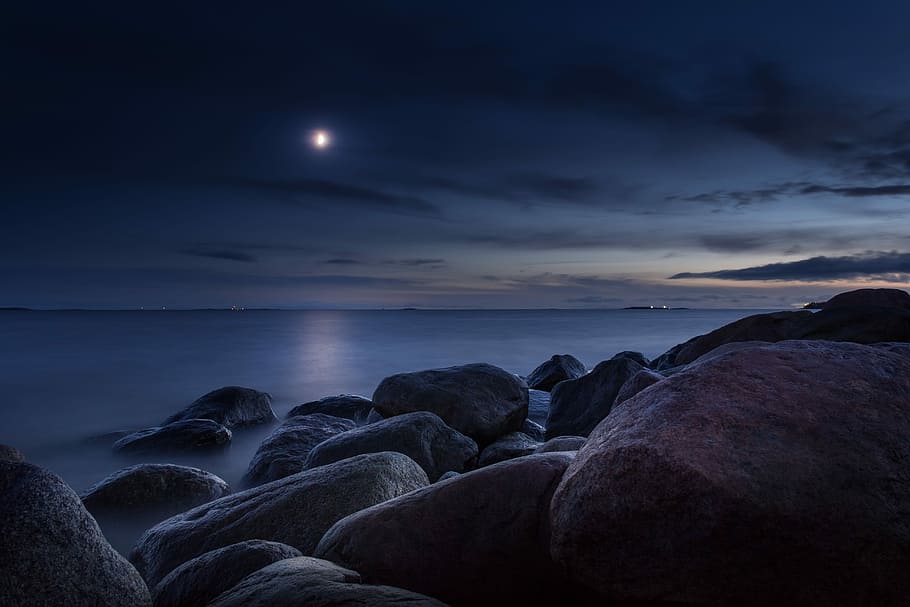 rocks near shore during nighttime, concrete rock fragments on body of water during night time