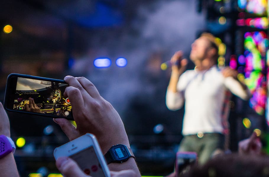 person taking video on person singing on stage selective focus photography HD wallpaper