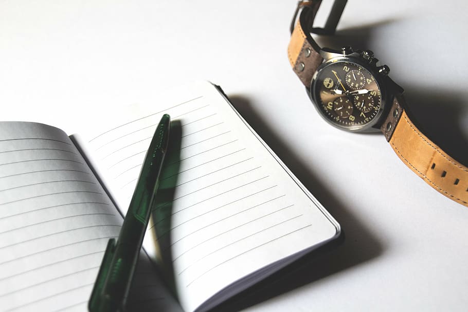 green click pen on white notebook beside round black chronograph watch with brown leather band HD wallpaper
