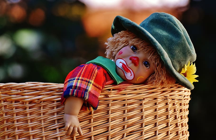 baby clown doll on basket, sad, colorful, sweet, funny, toys