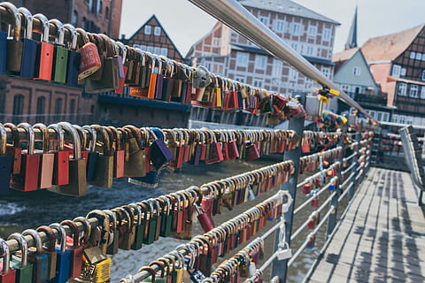 Love locks, padlocks on railings beside body of water and with houses behind HD wallpaper