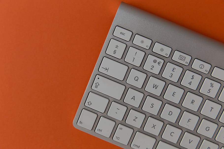 Apple wireless computer keyboard on orange background, technology HD wallpaper
