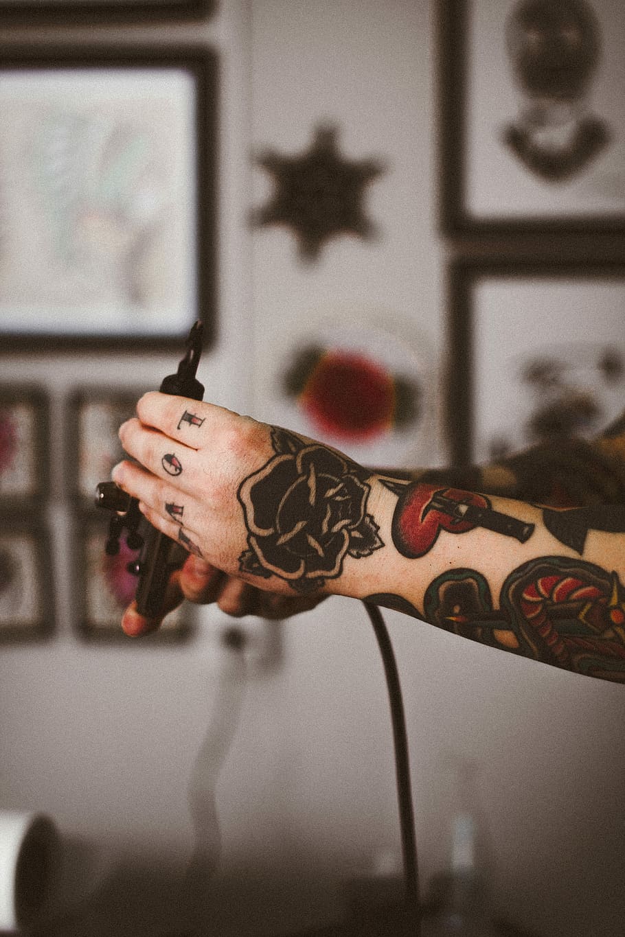 shallow focus photography of person holding black tattoo machine, person holding tattoo gun, HD wallpaper