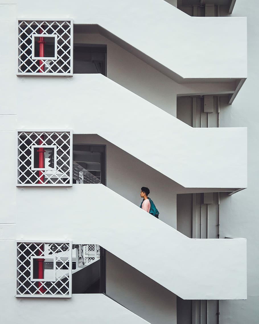 white concrete building, boy walking on white concrete house during daytime HD wallpaper