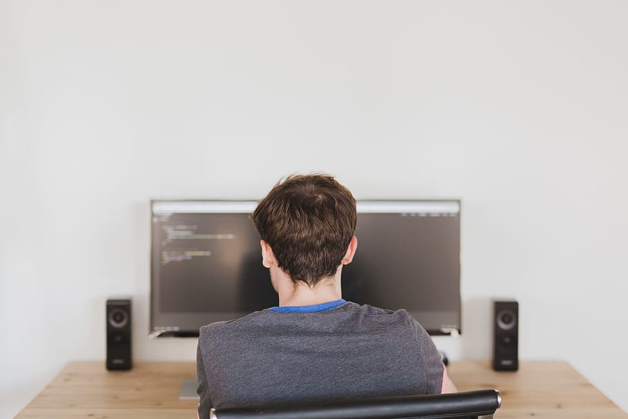 man sitting on chair infront of flat screen computer monitor HD wallpaper