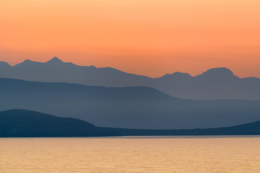 silhouette of mountains near body of water during golden hour, calm body of water near green tree mountains HD wallpaper