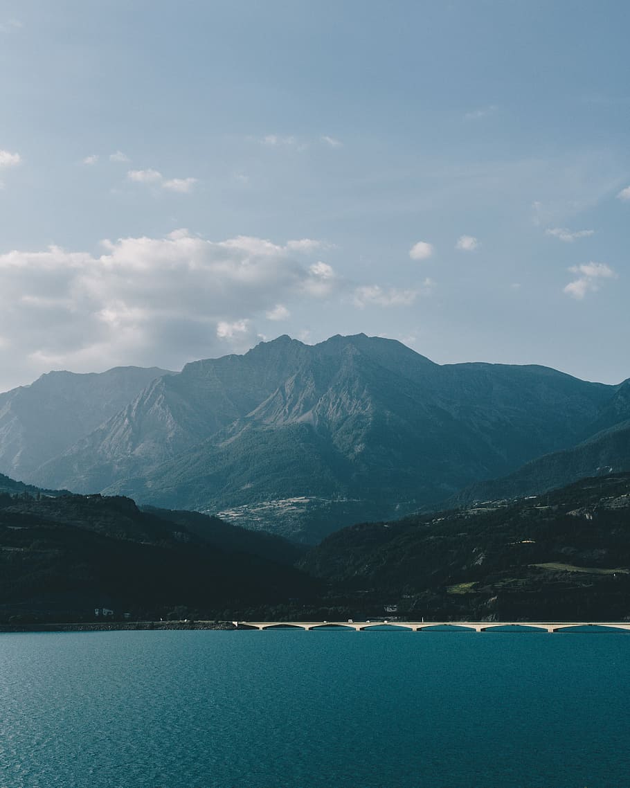 body of water and mountain, body of water near mountain at daytime HD wallpaper