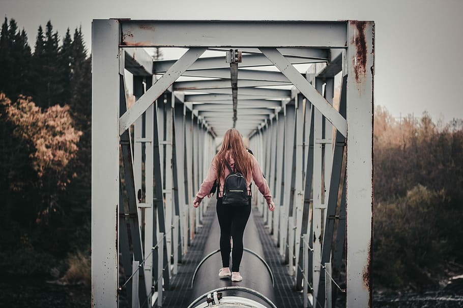 woman standing on black tunnel at daytime, woman walking on large black pipe HD wallpaper