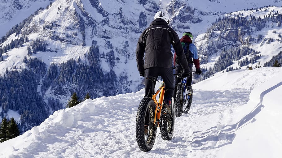 man riding yellow fat bike on snow-covered road, winter, mountain