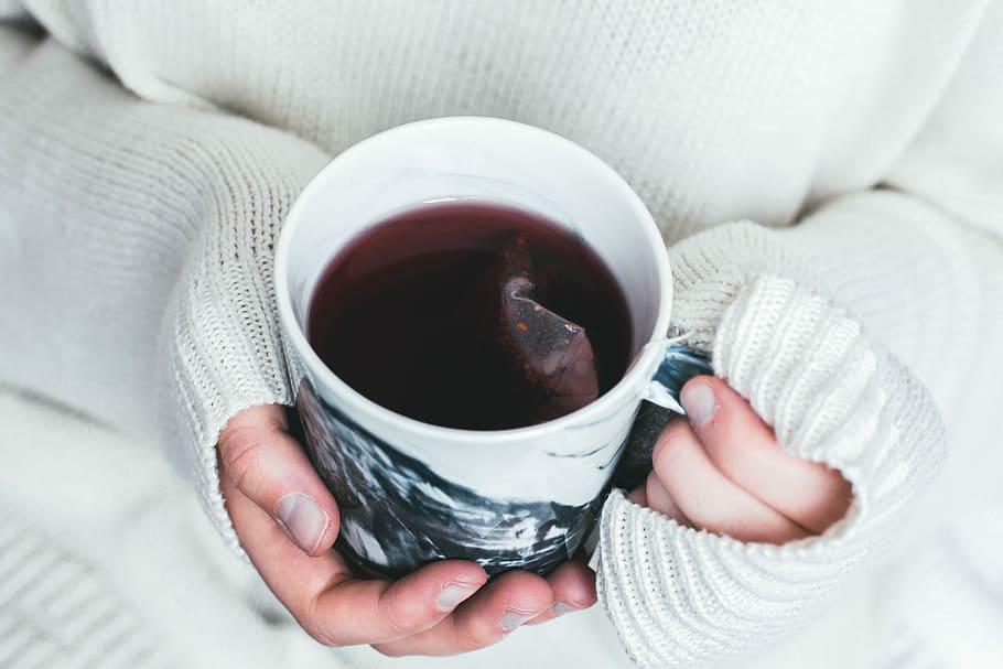 person holding white and black cup with teabag inside, person holding cup of coffee HD wallpaper