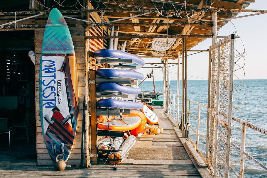 assorted-color paddleboards, assorted surfboard on racks, shed