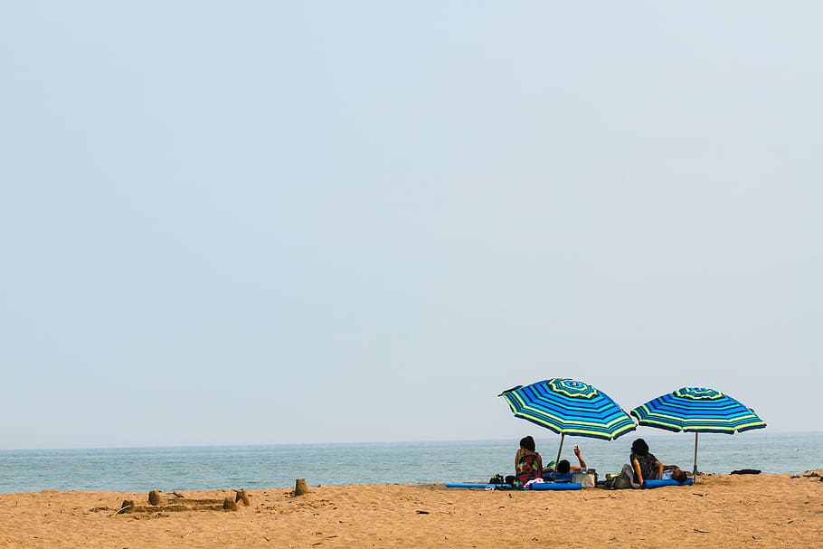 people lying on mat under green and blue umbrella during daytime, person sitting in front of beach HD wallpaper