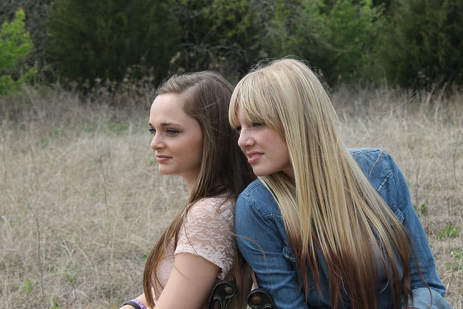 two women sitting down on brown grass field during daytime HD wallpaper