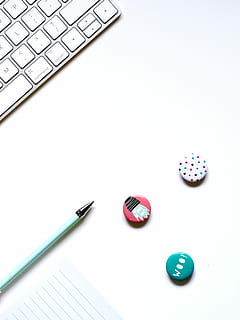 thre assorted button pins near green ballpoint pen, white keyboard beside pen on desk HD wallpaper
