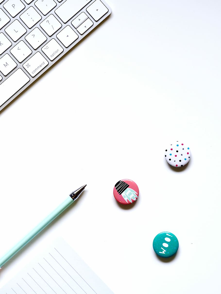 thre assorted button pins near green ballpoint pen, white keyboard beside pen on desk HD wallpaper