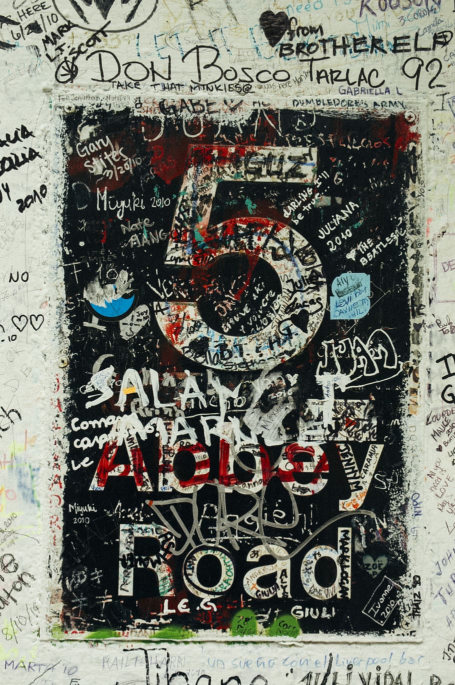 5 Abbey Road text with black background, white wall full of grafitti