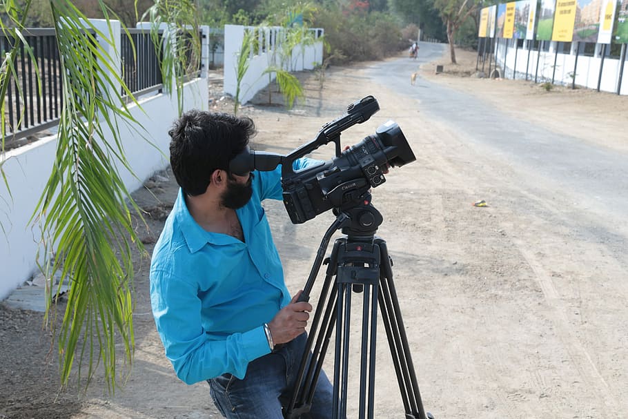 man in blue dress shirt using video camera near road, Shooting