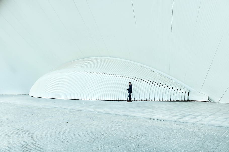 person wearing black long-sleeved top standing near white structure, man standing near gray metal frame HD wallpaper
