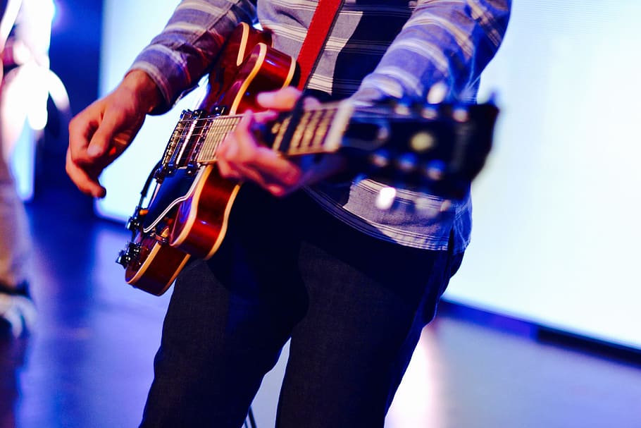 Man playing guitar on stage at a music concert, people, musician