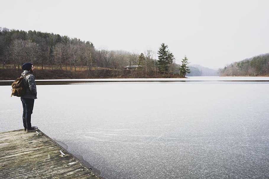 woman standing in front of lake while staring at it, photo of person standing on dock facing body of water HD wallpaper