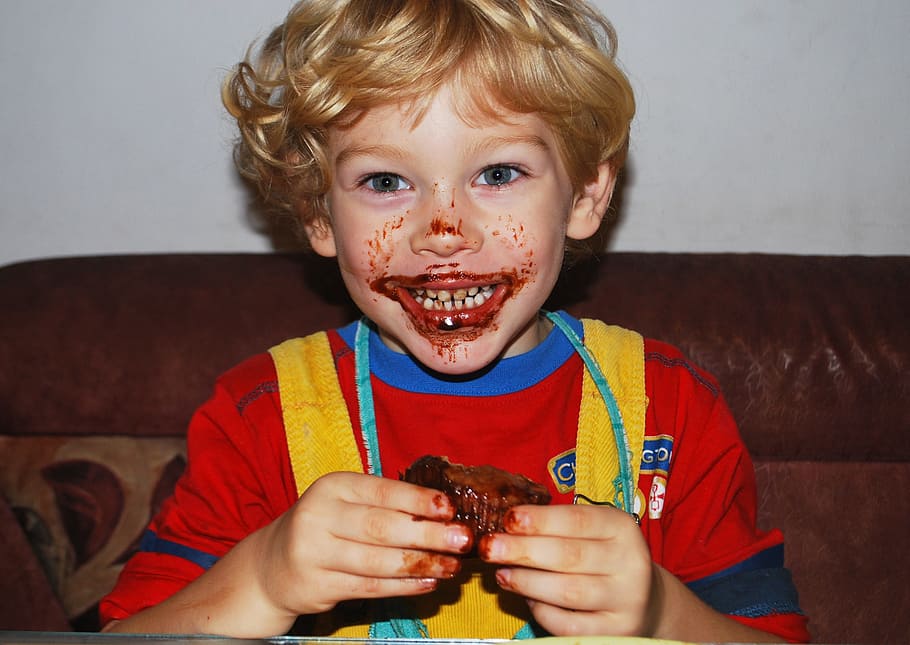boy wearing red and blue crew-neck shirt, eating, chocolate, muffin