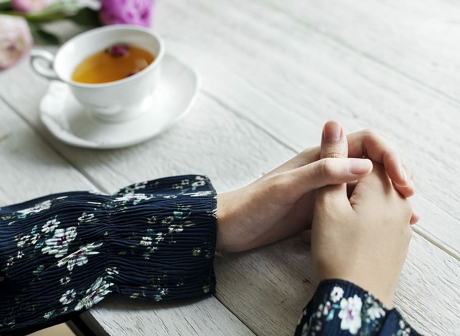 woman's hand near white ceramic teacup and saucer on brown wooden table HD wallpaper