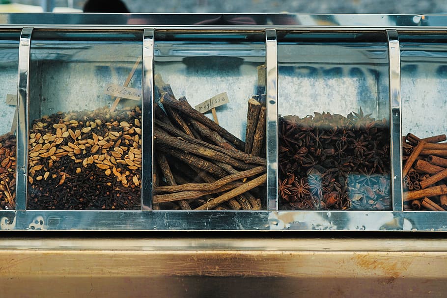 focus photography of assorted spices on display counter, stainless steel framed container with nuts and star anise HD wallpaper