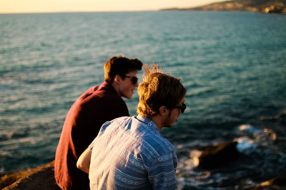 two man wearing black sunglasses beside on body of water during daytime HD wallpaper