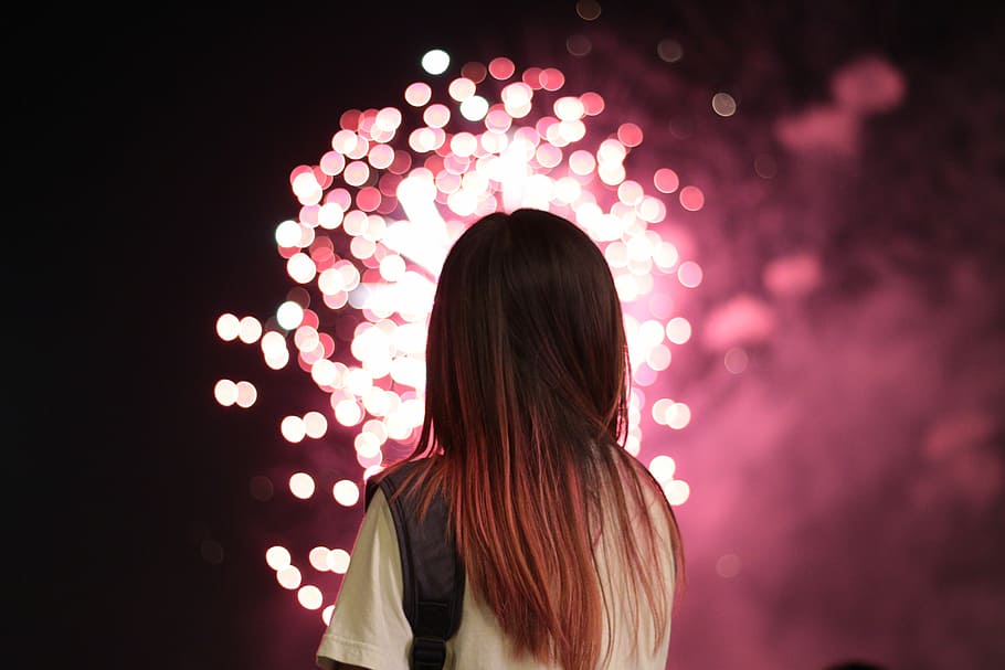 woman staring at fireworks, bokeh photograph of woman in white shirt