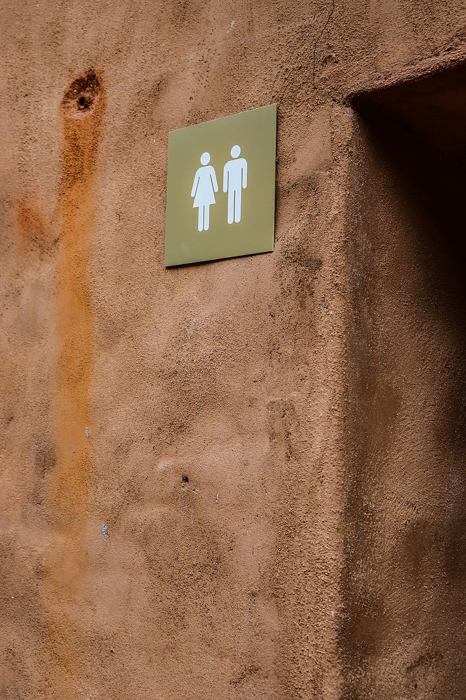 bathroom signage on brown wall, male and female signage mounted on brown concrete wall