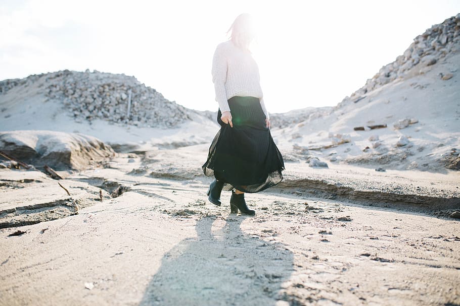 woman in black skirt walking on gray flooring, woman standing on snowy mountain