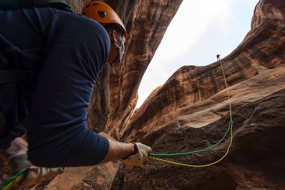 low angle view of man under cliff holding rope, climbing, rappelling