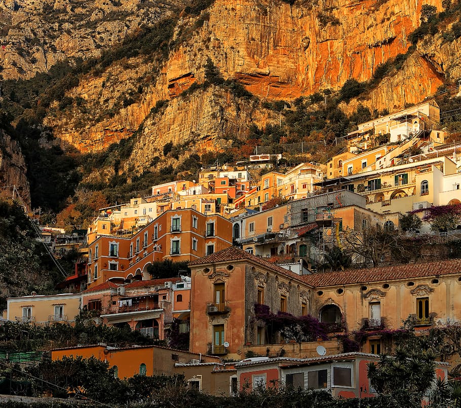 town near cliff, brown concrete houses near mountain at daytime HD wallpaper